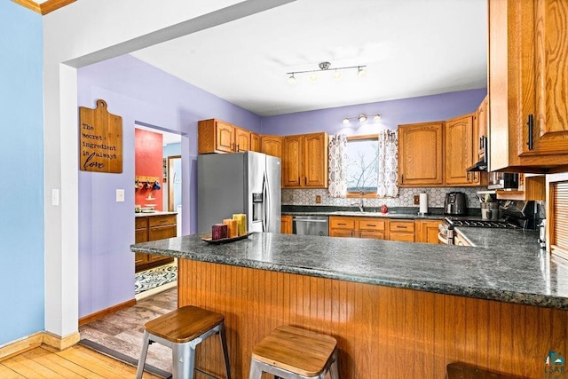 kitchen with a peninsula, dark countertops, stainless steel appliances, and decorative backsplash