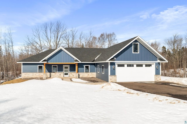 craftsman inspired home featuring board and batten siding, stone siding, a garage, and aphalt driveway