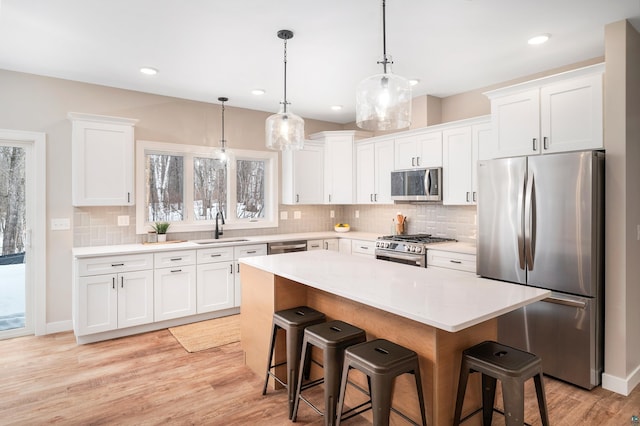 kitchen with stainless steel appliances, light wood-style floors, a sink, and a kitchen breakfast bar