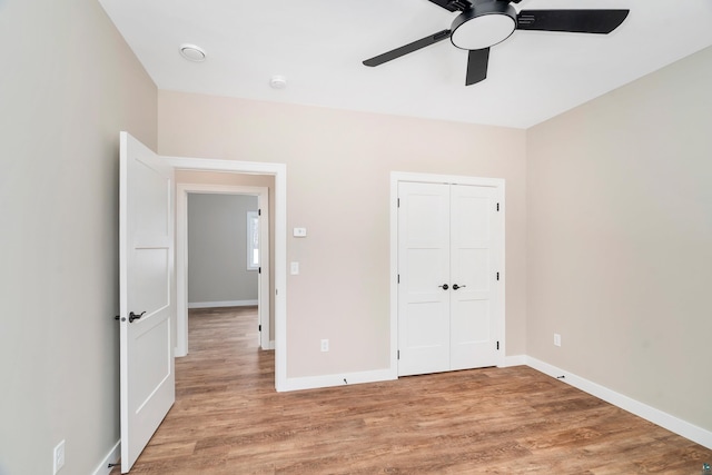 unfurnished bedroom with ceiling fan, light wood-style flooring, and baseboards