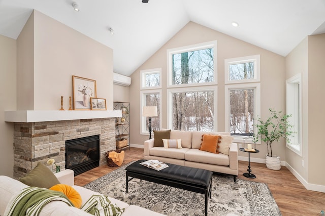 living area with a wall mounted air conditioner, a fireplace, baseboards, and wood finished floors