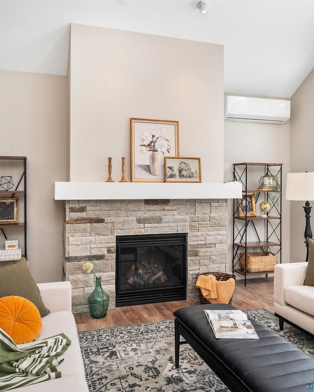 living area with a fireplace, a wall unit AC, and wood finished floors