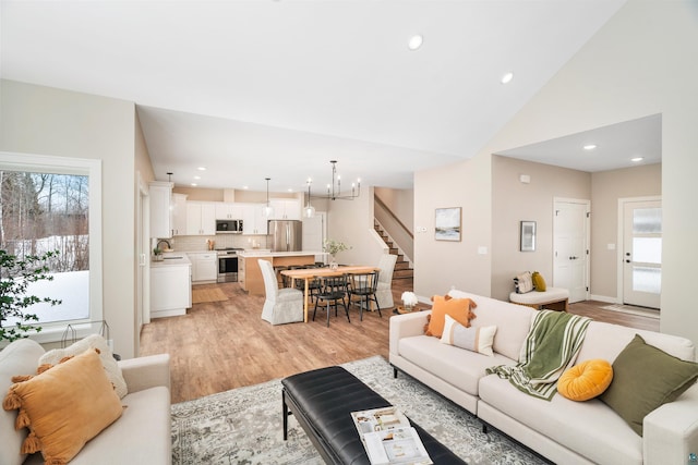 living room featuring recessed lighting, a notable chandelier, light wood finished floors, and stairs