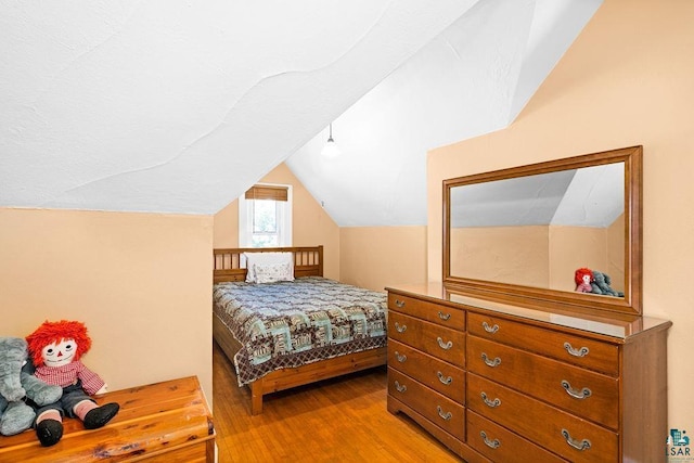 bedroom with lofted ceiling and light wood-style floors