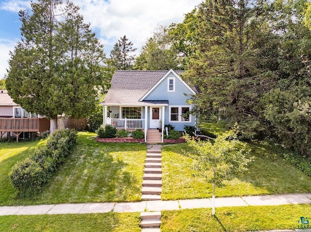 view of front of house featuring covered porch, a shingled roof, and a front yard