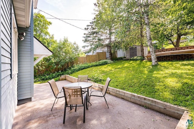 view of patio / terrace with an outbuilding, outdoor dining area, and a fenced backyard