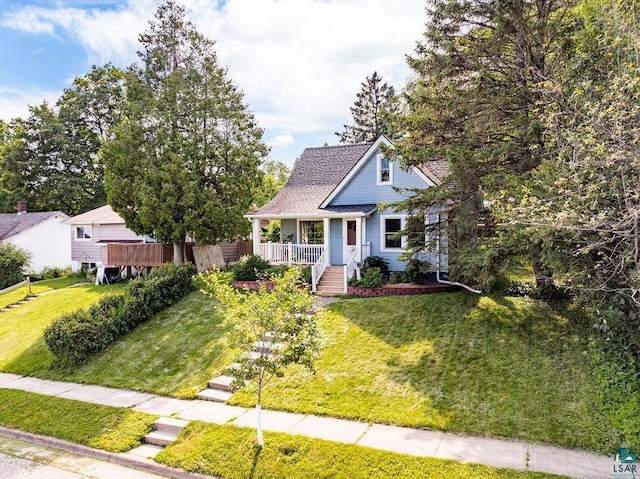 view of front of home featuring a shingled roof, covered porch, and a front lawn