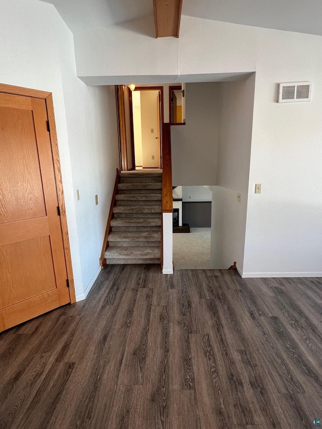 empty room with stairway, baseboards, visible vents, and dark wood-type flooring