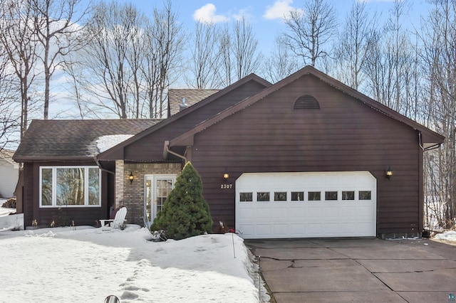 rustic home with driveway, brick siding, an attached garage, and a shingled roof