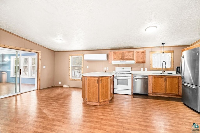 kitchen with under cabinet range hood, stainless steel appliances, a sink, an AC wall unit, and light countertops