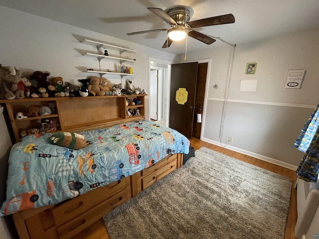 bedroom featuring wood finished floors, a ceiling fan, and baseboards