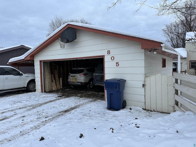 snow covered garage featuring fence