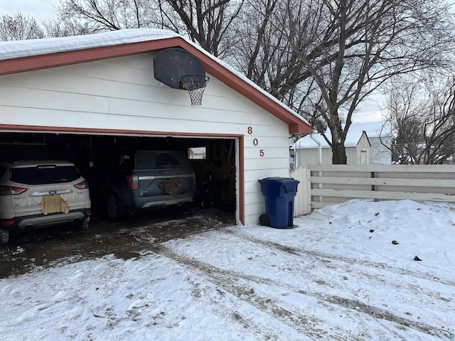 snow covered garage with fence