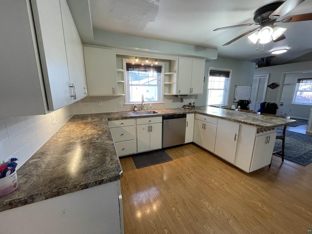 kitchen featuring wood finished floors, a sink, stainless steel dishwasher, open shelves, and dark countertops