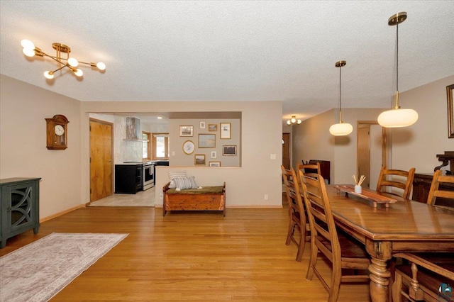 dining space with baseboards, light wood-style flooring, and a textured ceiling