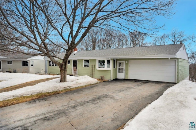 ranch-style house with a garage, driveway, and a shingled roof