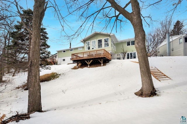 snow covered back of property featuring a deck