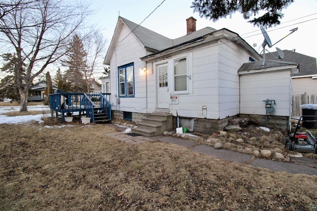 view of front facade featuring entry steps, a deck, and a chimney