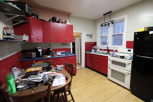 kitchen featuring red cabinets, light wood finished floors, freestanding refrigerator, a sink, and double oven range