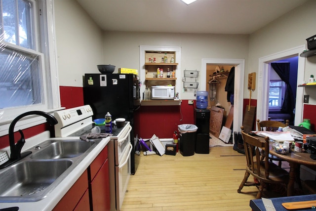 kitchen with white appliances, a sink, and light wood-style floors