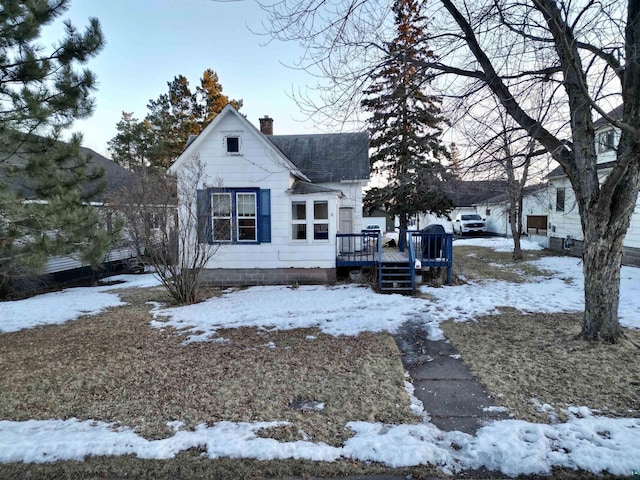 bungalow featuring a chimney, a deck, and roof with shingles