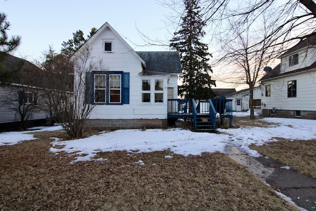 view of front facade with a shingled roof and a wooden deck