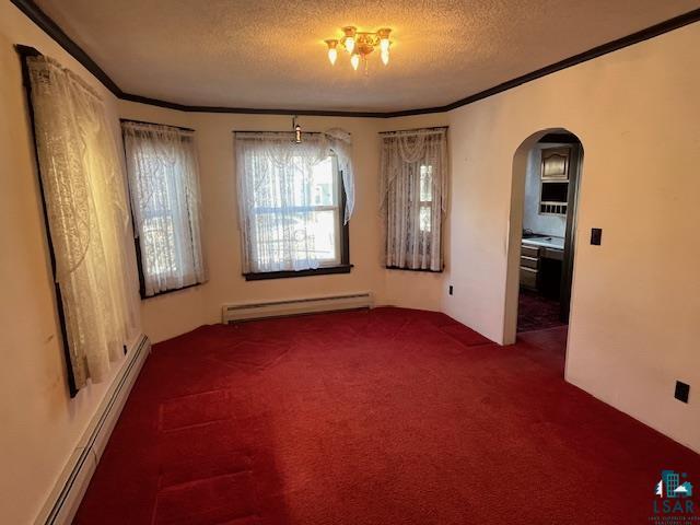 spare room with a baseboard radiator, arched walkways, baseboard heating, and a textured ceiling