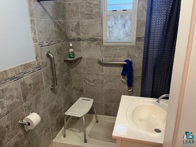 bathroom with tiled shower and vanity