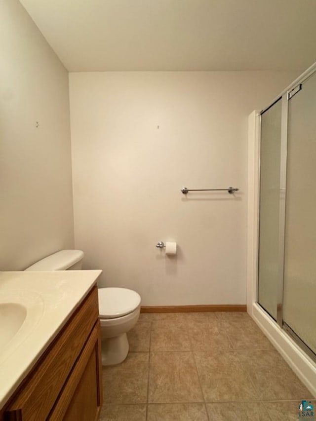 full bath featuring a stall shower, vanity, toilet, and baseboards