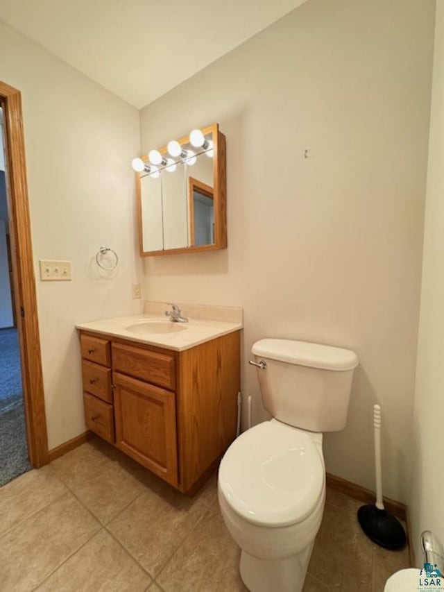 half bathroom with baseboards, vanity, toilet, and tile patterned floors