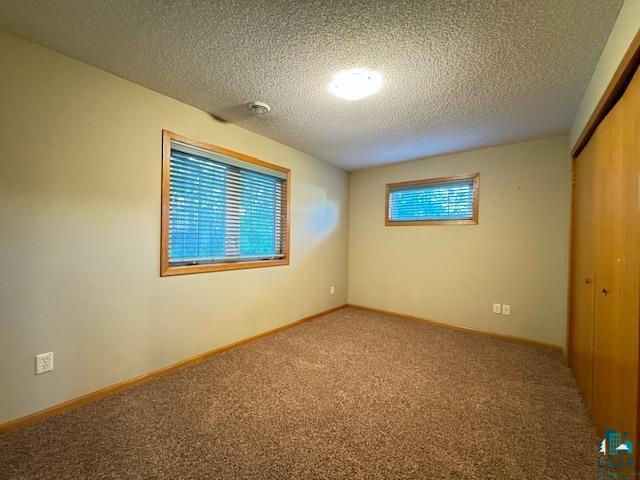 carpeted spare room featuring baseboards and a textured ceiling