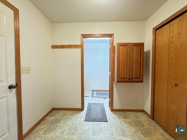 hall with a textured ceiling and baseboards