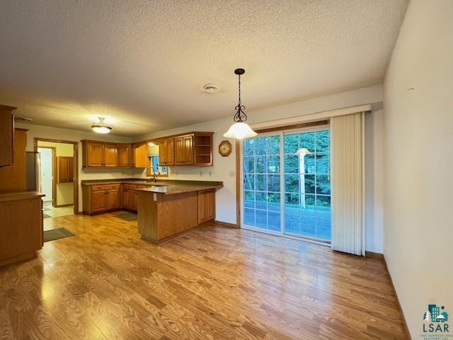 kitchen with a peninsula, light wood finished floors, open shelves, and brown cabinets