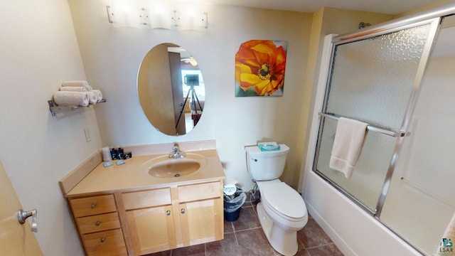 full bath with combined bath / shower with glass door, tile patterned flooring, vanity, and toilet