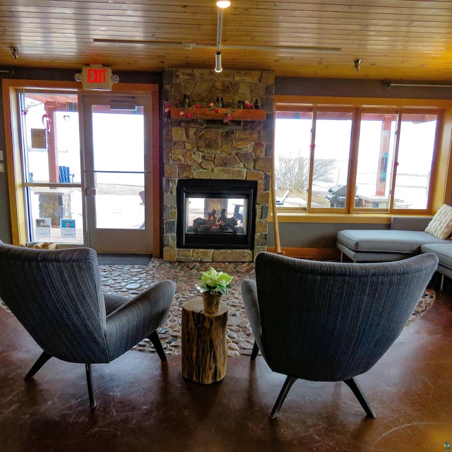 living area with a stone fireplace and wood ceiling