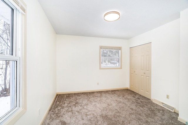 unfurnished bedroom featuring a closet, carpet flooring, visible vents, and baseboards