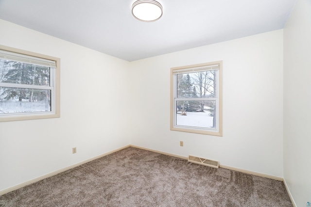 carpeted empty room with visible vents and baseboards