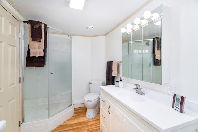 full bath with toilet, wood finished floors, vanity, ornamental molding, and a stall shower