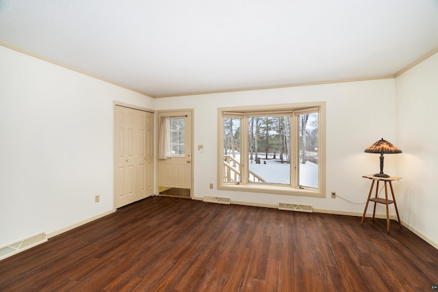 empty room with dark wood-style floors, visible vents, and baseboards