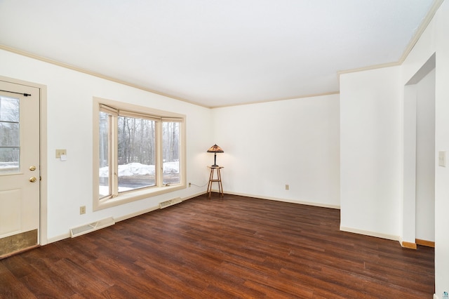 empty room featuring a wealth of natural light, wood finished floors, visible vents, and crown molding