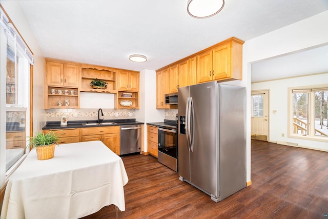 kitchen with dark countertops, dark wood-style floors, appliances with stainless steel finishes, open shelves, and a sink