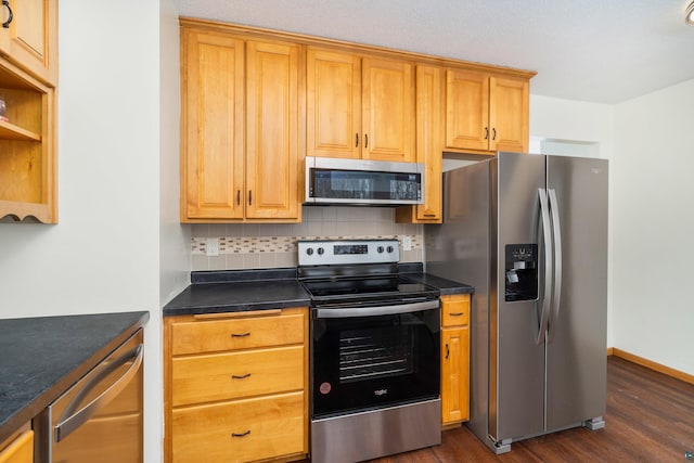 kitchen with tasteful backsplash, baseboards, dark countertops, dark wood-style flooring, and stainless steel appliances