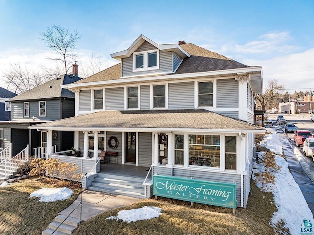 american foursquare style home featuring covered porch, a shingled roof, and a chimney