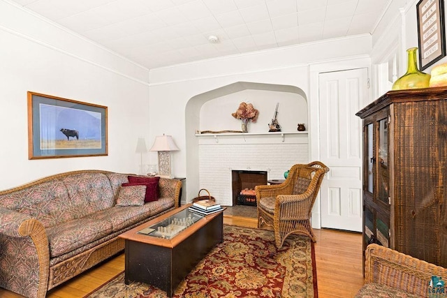 living area featuring a fireplace, ornamental molding, and wood finished floors