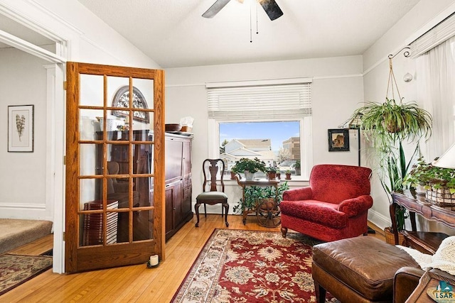 living area with lofted ceiling, ceiling fan, and light wood-type flooring