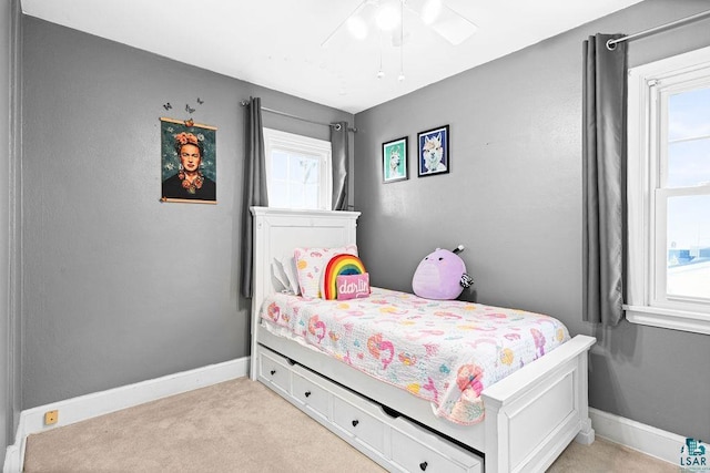 bedroom with a ceiling fan, light carpet, and baseboards