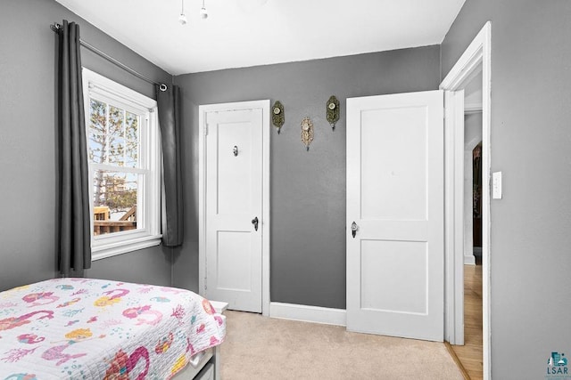 bedroom featuring light carpet and baseboards