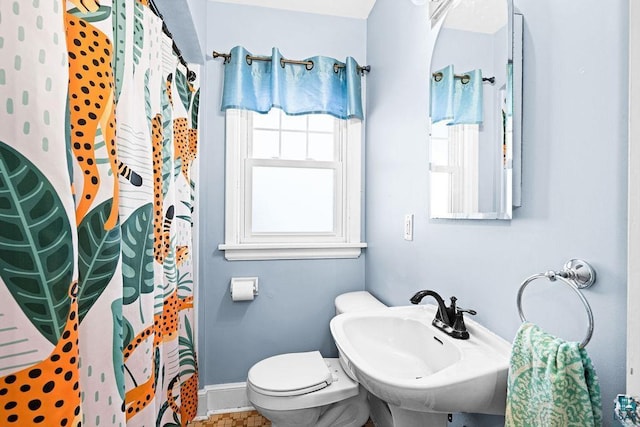 full bathroom featuring a shower with shower curtain, a sink, toilet, and baseboards