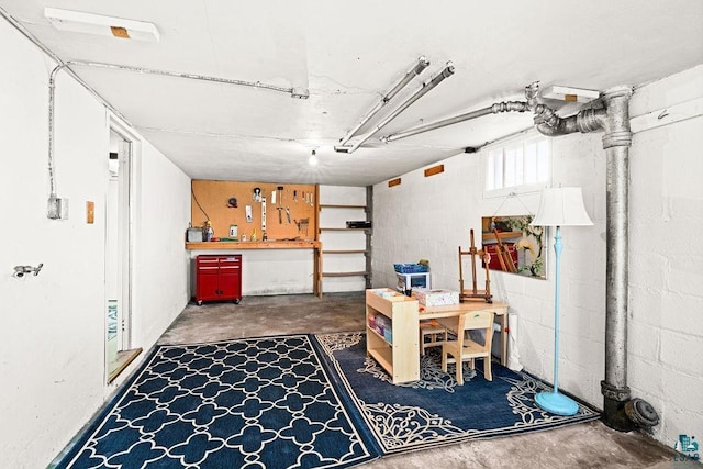 basement with concrete block wall, a garage, and a workshop area