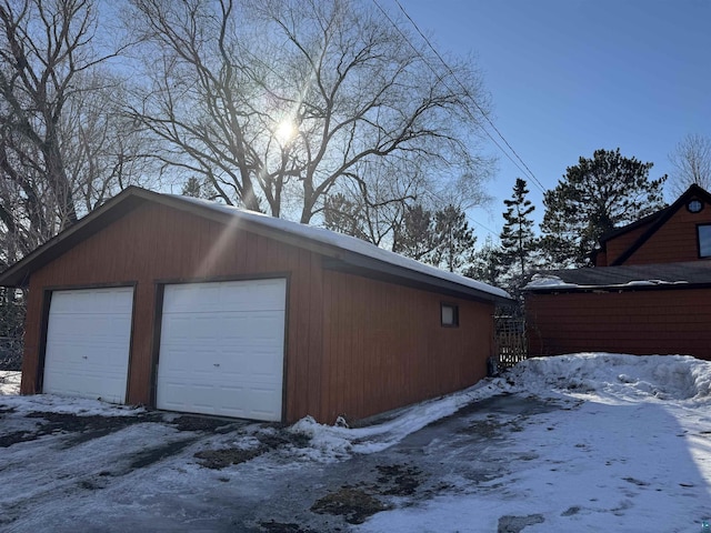 snow covered garage with a detached garage